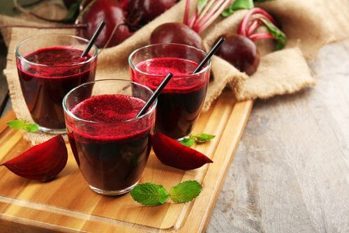 Three cups of beet juice with straws in them.