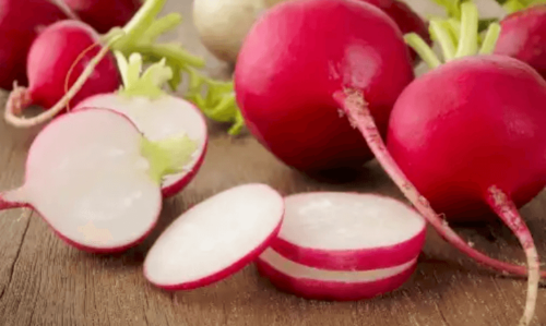 Whole and cut radishes on a board.