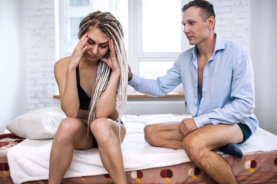 A couple sitting in bed having a hard time talking about sex.