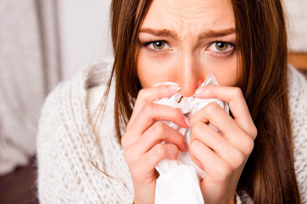 A woman with allergies sneezing.