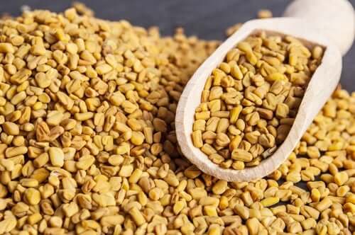 Fenugreek seeds with a wooden scoop.