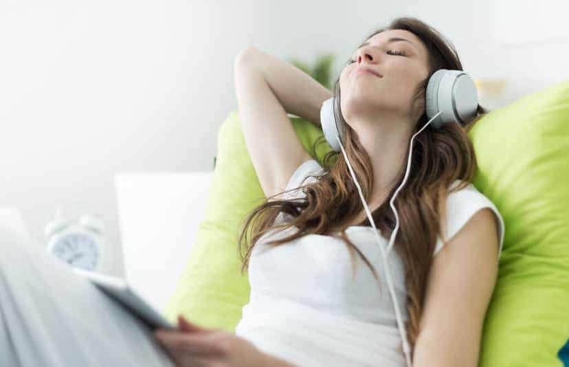 A woman sitting back and relaxing while listening to music on her headphones.