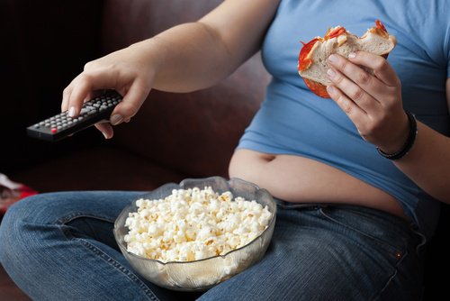 Woman eating junk food and watching television