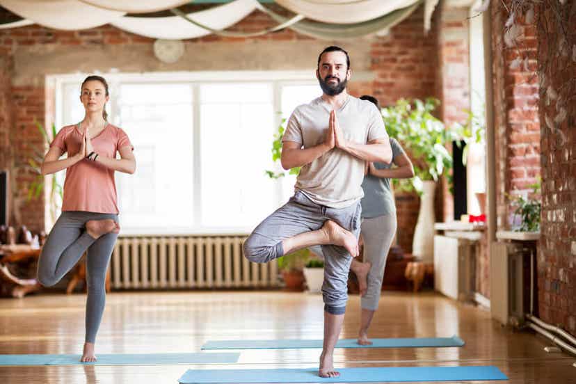 Adults doing the tree pose in a gym class.