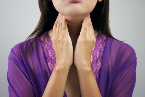 Woman with thyroid problem touching her neck