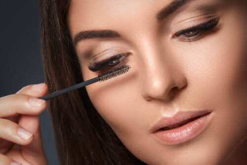 A woman with droopy eyelids putting on mascara.