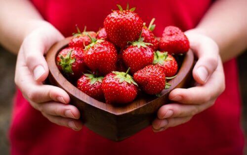 A woman holding a bowl of strawberries.