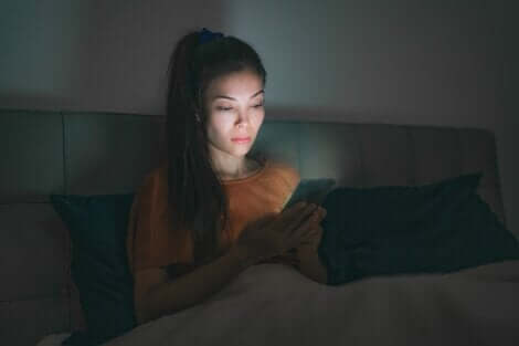 A woman using her cell phone in bed.
