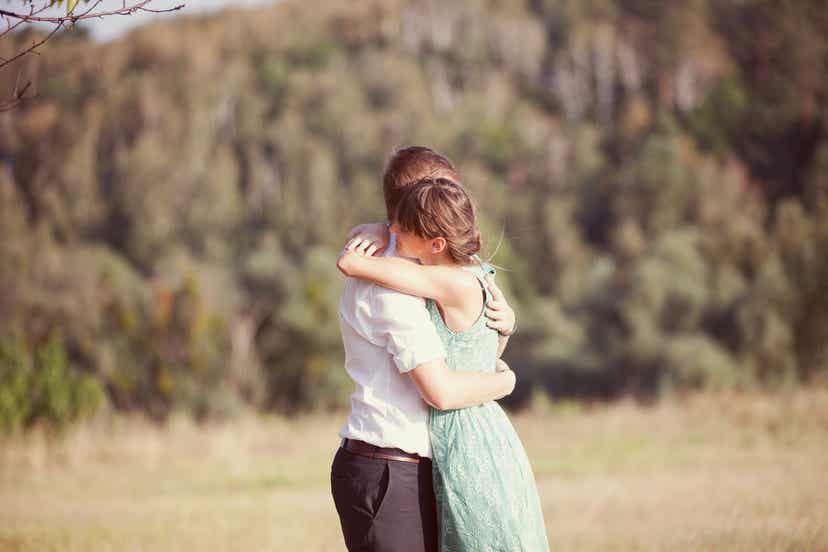 A couple embracing in a field.