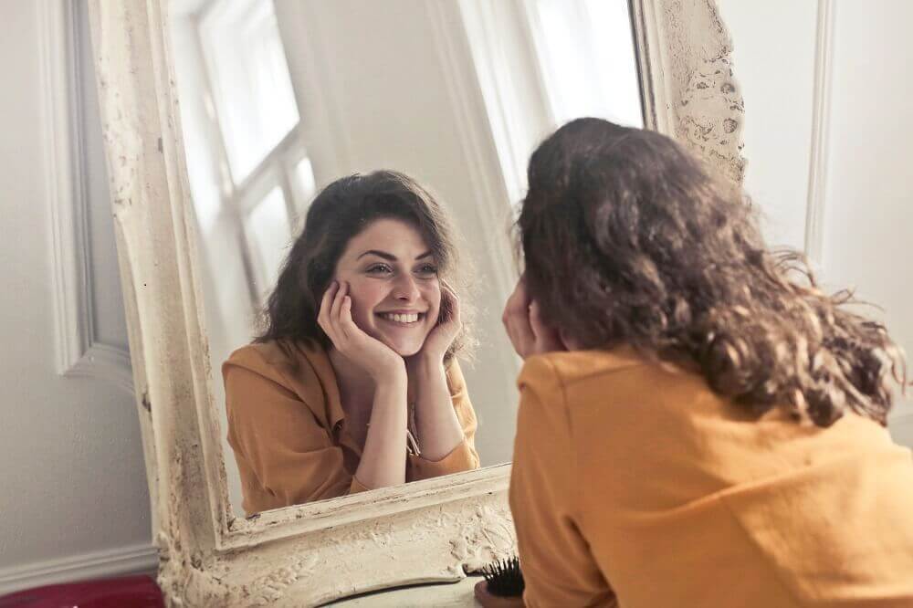 A woman smiling into the mirror.