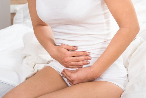 Woman with menopause symptoms holds abdomen flaxseed