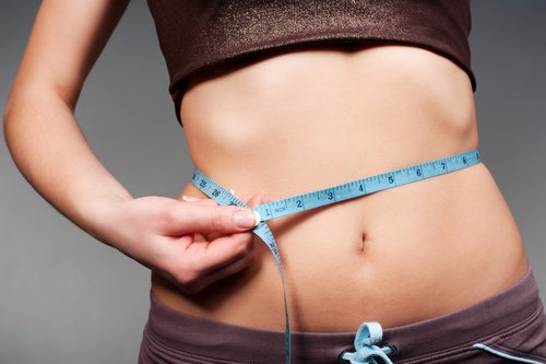 Woman measuring waist with tape measurer
