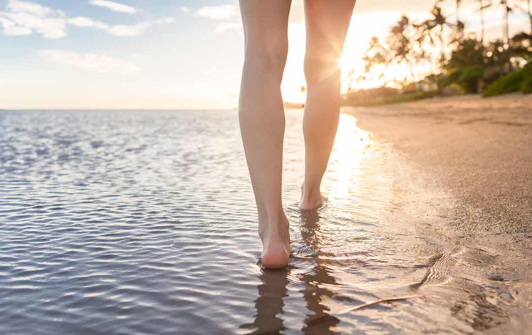 A woman walking along a tropical beach.
