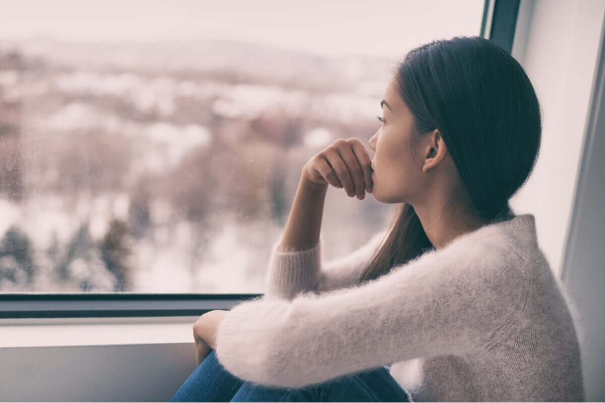 A woman gazing out the window at a wintery landscape.