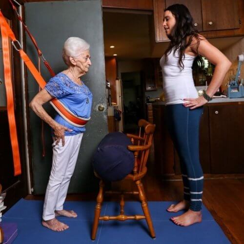 An elderly woman using belts to train in yoga.