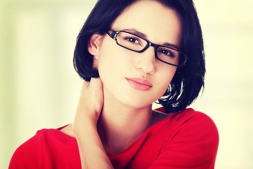 A wman in red with glasses touching her neck.