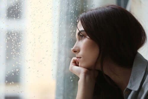 Woman looking out a window at the rain.