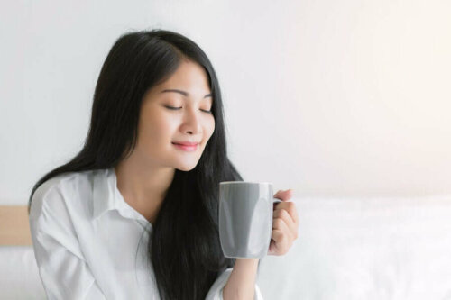A woman enjoying a cup of warm water and honey.