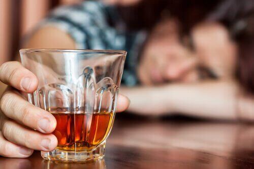 Glass of liquor on a table woman sleeping on bar