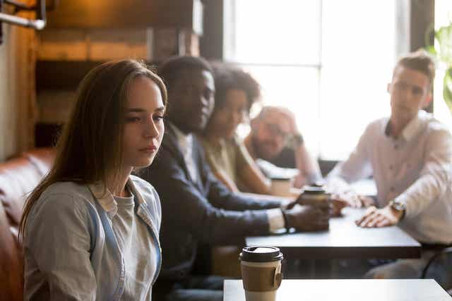 A woman sitting alone at a restaurant, turning away from the people at the next table.