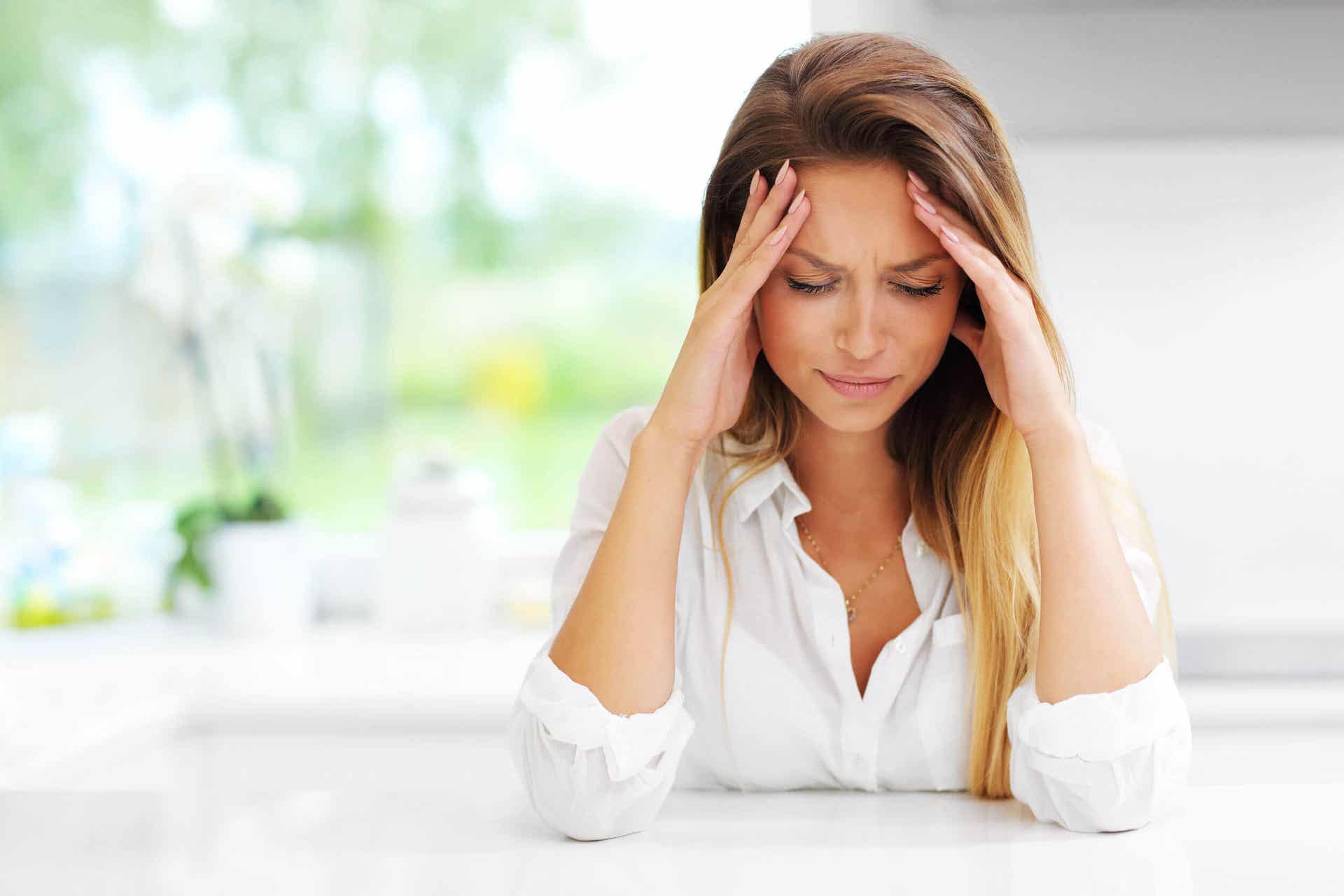A woman holding her head in her hands, looking stressed.