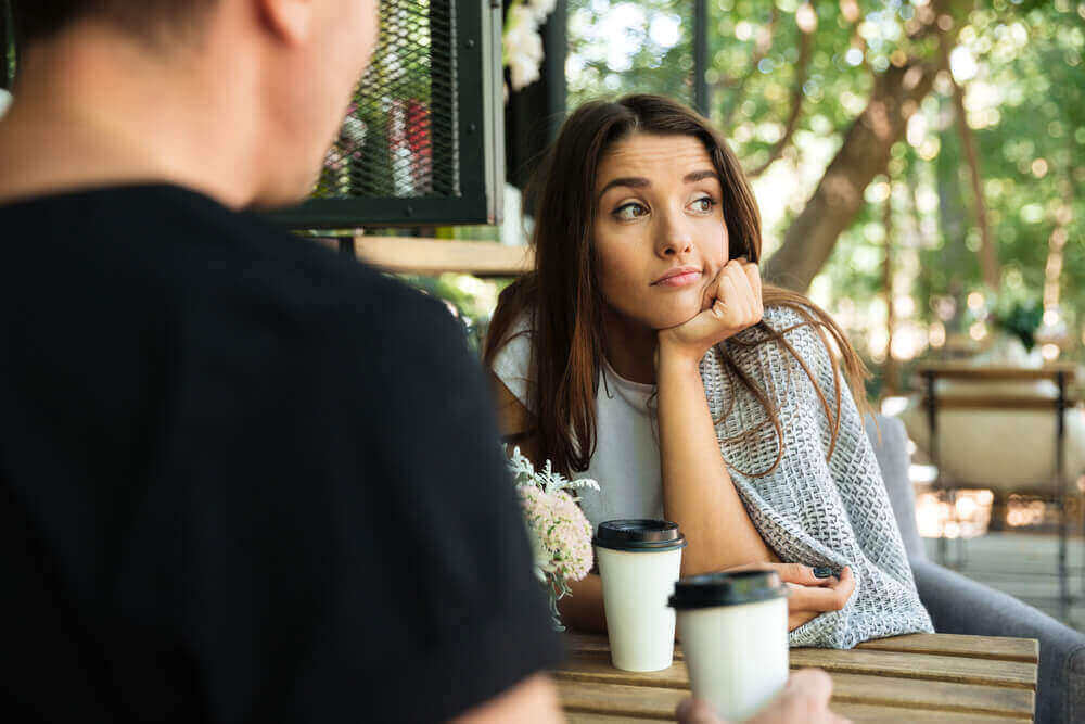 couple sat at a table and the woman doesn't want to be there