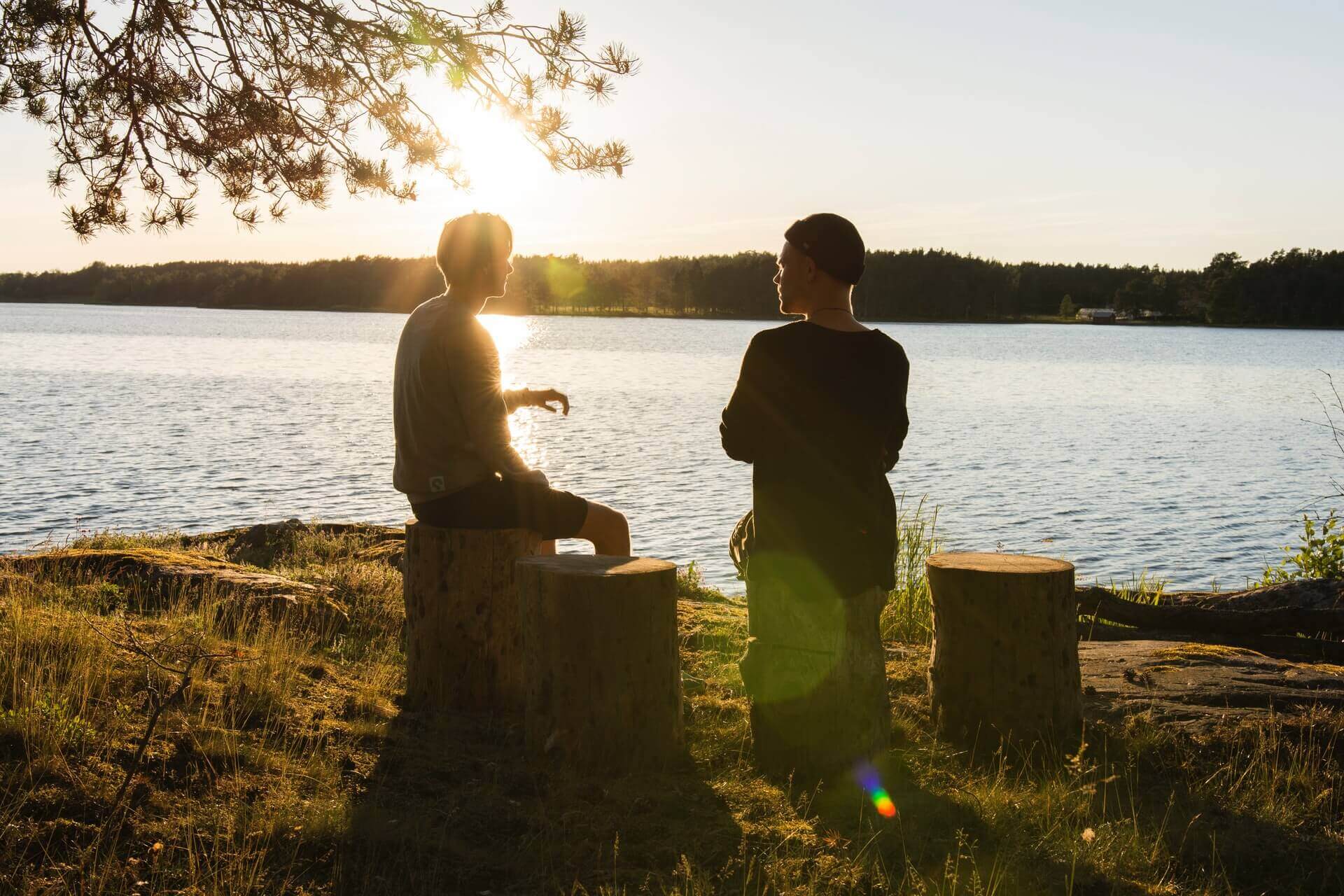 Friends talking by a lake at dusk.