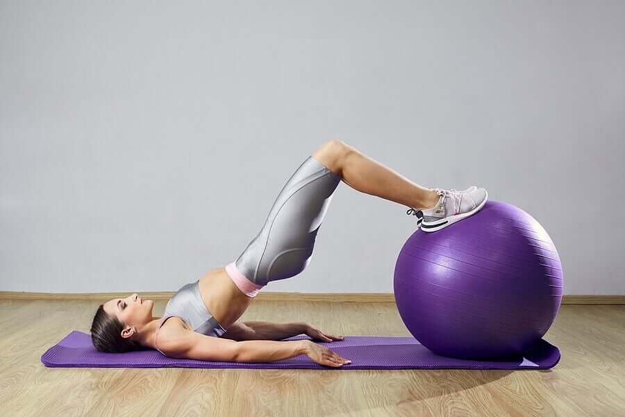 A woman lifting her pelvis using an exercise ball.