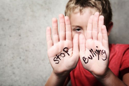 Chłopiec z napisem na dłoniach: stop bullying