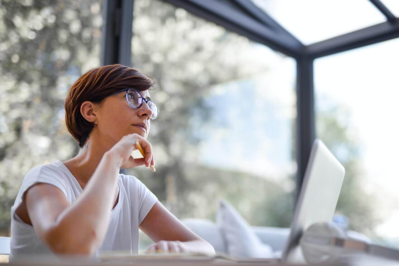 A woman looking thoughtfully at someone from behind her desk.