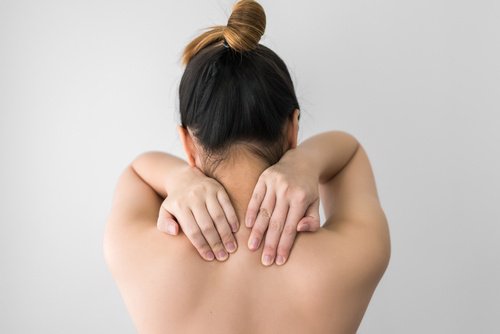 Woman touching her upper back with both hands uses for vicks vaporub