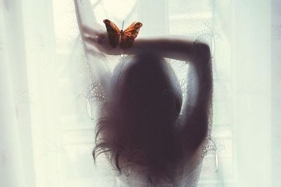 A butterfly sitting on the arm of a woman