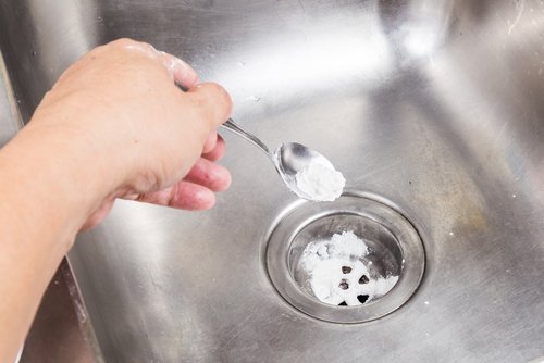 Person putting baking soda down the drain