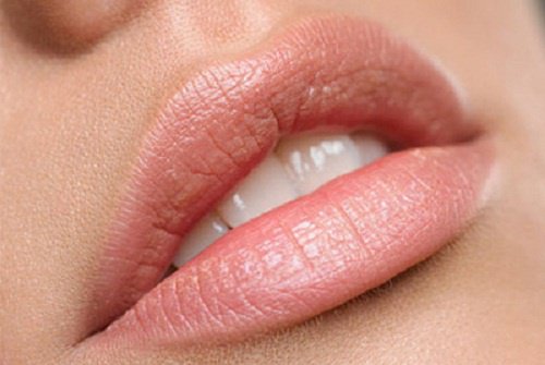 Kvinde bruger makeup til at få fyldigere læber