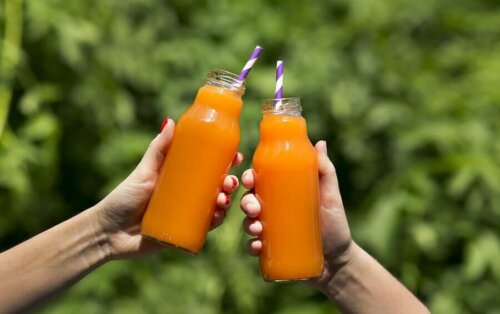 People holding bottles of carrot and ginger juice.