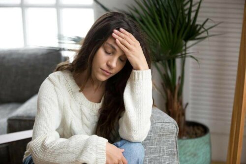 A tired woman holding her forehead.