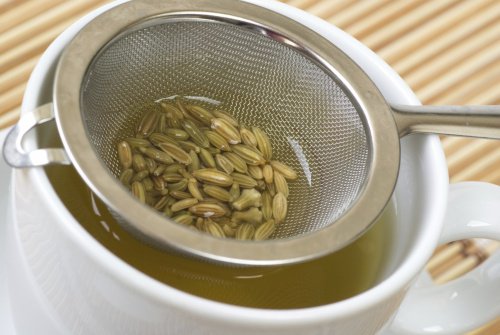 Fennel seeds in strainer inside teacup fennel tea fight digestive problems