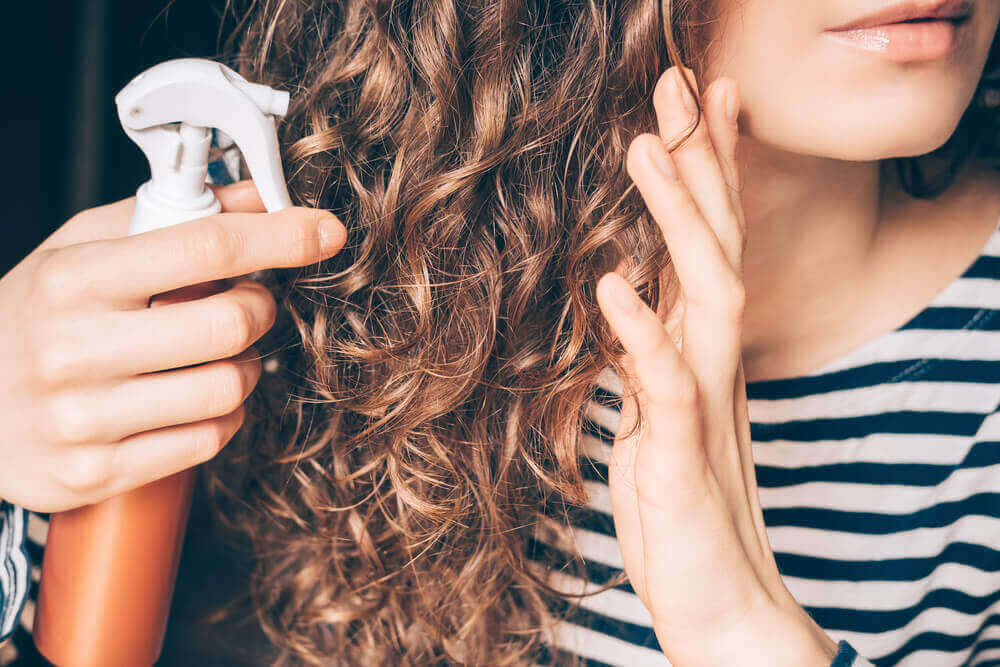 A girl applying coconut oil to her hair.