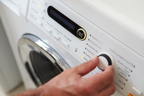 Person touching the buttons on a modern washing machine naturally eliminate mildew