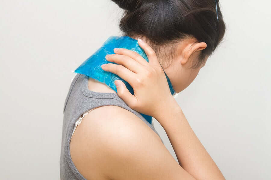 A woman placing and ice pack on her neck.