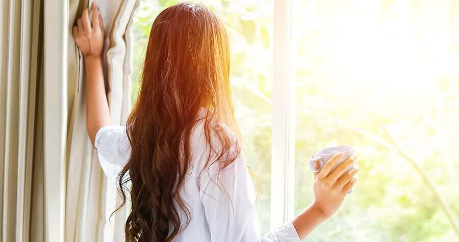 A woman looking out the window on a sunny morning.