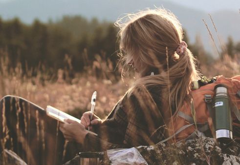 Girl in meadow writing dreams in diary your subconscious is translated into dreams you can bear