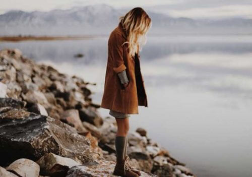A woman on a rocky lake shore.