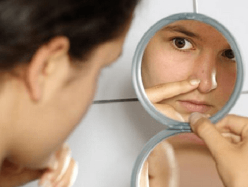 Woman looking at her blackheads in the mirror