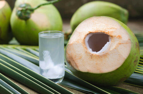 A glass of coconut water next to a coconut.