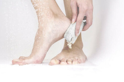 A person rubbing their cracked heels with a pumice stone.