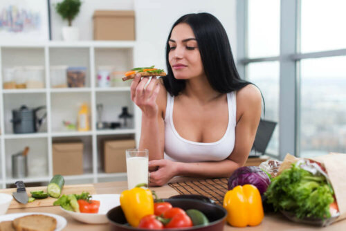 A woman eating toast and vegetables.