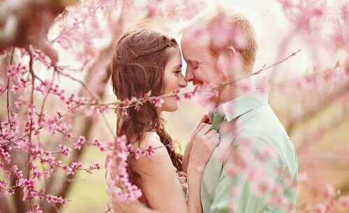 a happy couple surrounded by trees with pink flowers