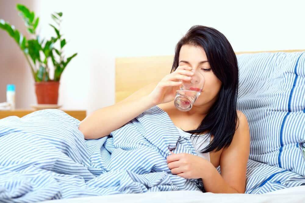 A woman drinking water in bed, first thing in the morning.