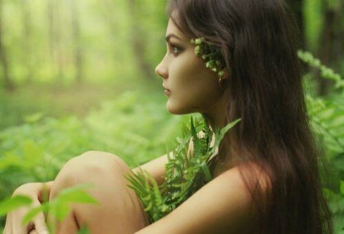 Faerie woman with plants as clothes sits in forest contemplating fight mental exhaustion